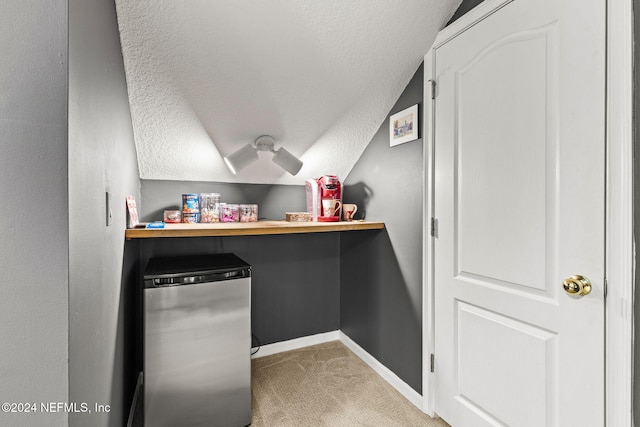 interior space featuring lofted ceiling, light carpet, baseboards, and a textured ceiling