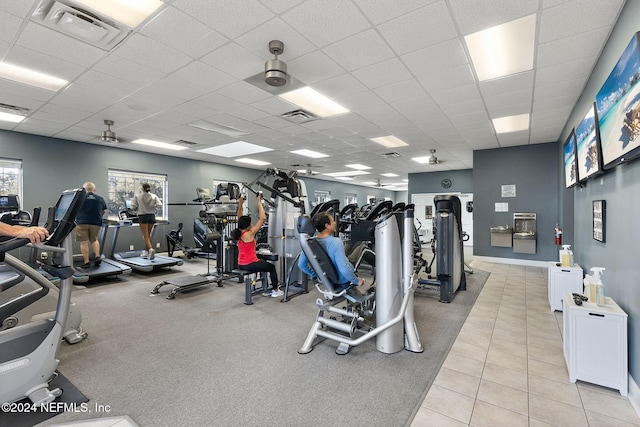 gym with light tile patterned floors, a paneled ceiling, and visible vents