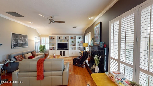 living area with wood finished floors, visible vents, lofted ceiling, ceiling fan, and ornamental molding