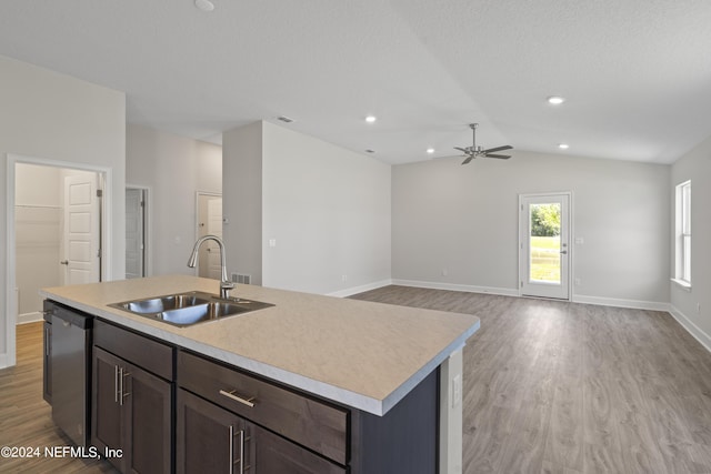 kitchen featuring vaulted ceiling, a kitchen island with sink, sink, dishwasher, and light hardwood / wood-style floors