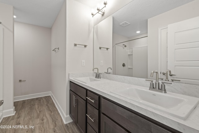 bathroom with vanity, a textured ceiling, hardwood / wood-style flooring, and walk in shower