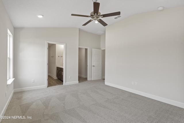 unfurnished bedroom featuring carpet, ensuite bath, ceiling fan, and lofted ceiling