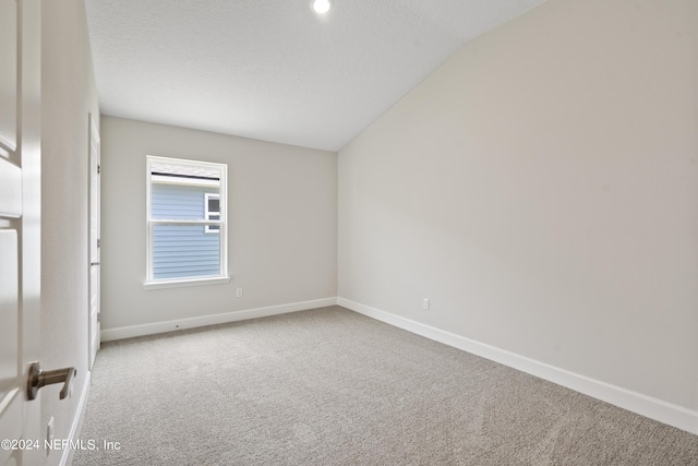 carpeted spare room featuring a textured ceiling and lofted ceiling