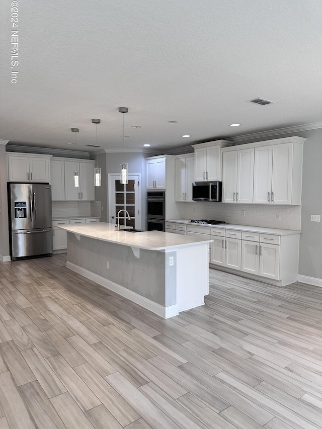 kitchen featuring appliances with stainless steel finishes, decorative light fixtures, light hardwood / wood-style flooring, and white cabinetry