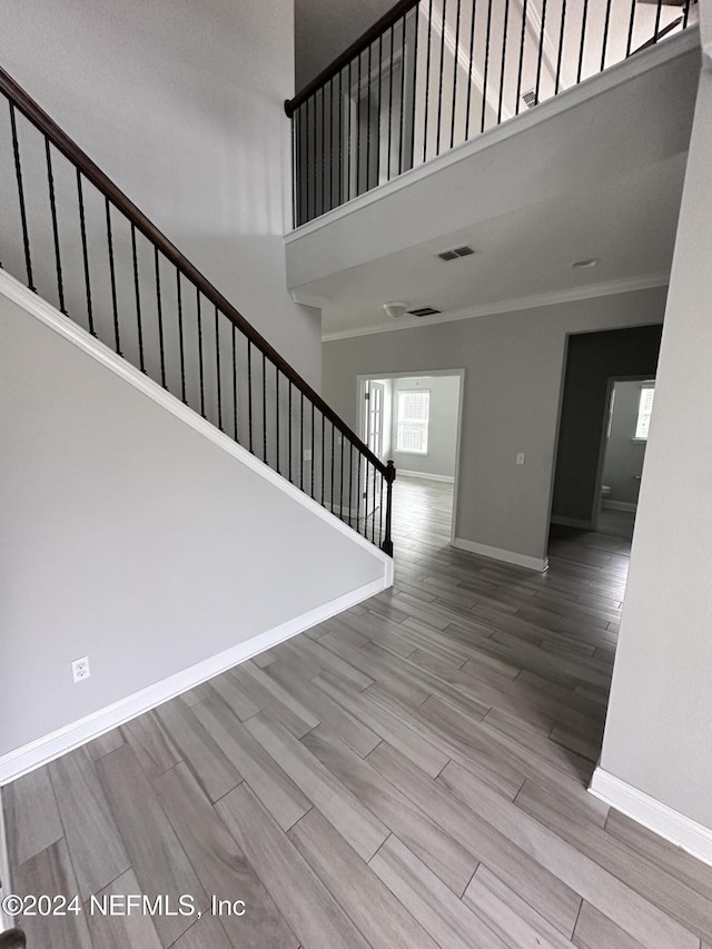 interior space with crown molding, a high ceiling, and hardwood / wood-style flooring