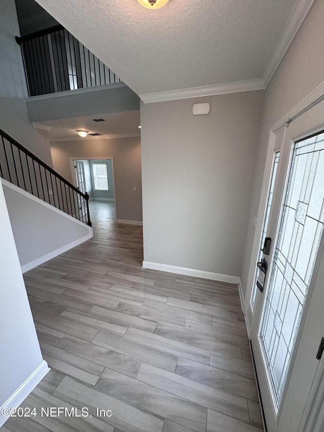 entryway with crown molding, a textured ceiling, and light wood-type flooring