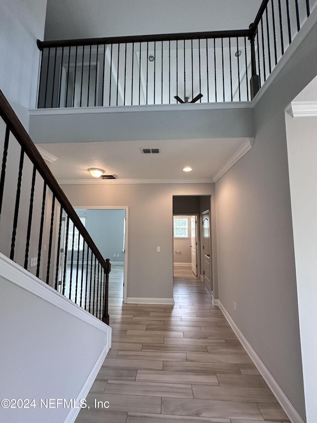 interior space featuring hardwood / wood-style flooring, a towering ceiling, and crown molding