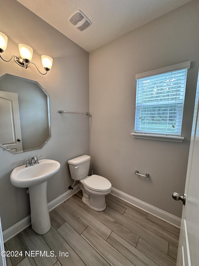 bathroom featuring hardwood / wood-style floors, toilet, and a textured ceiling