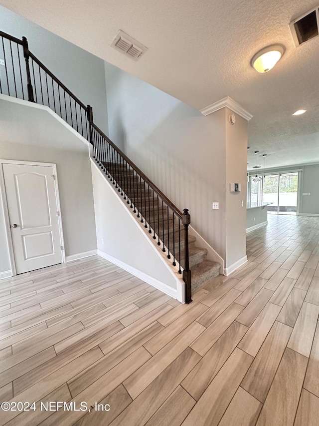 stairway with hardwood / wood-style flooring and a textured ceiling