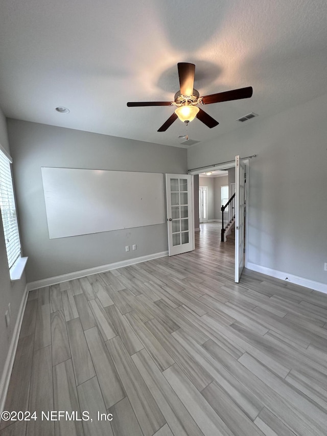 spare room with ceiling fan, light hardwood / wood-style flooring, and a textured ceiling