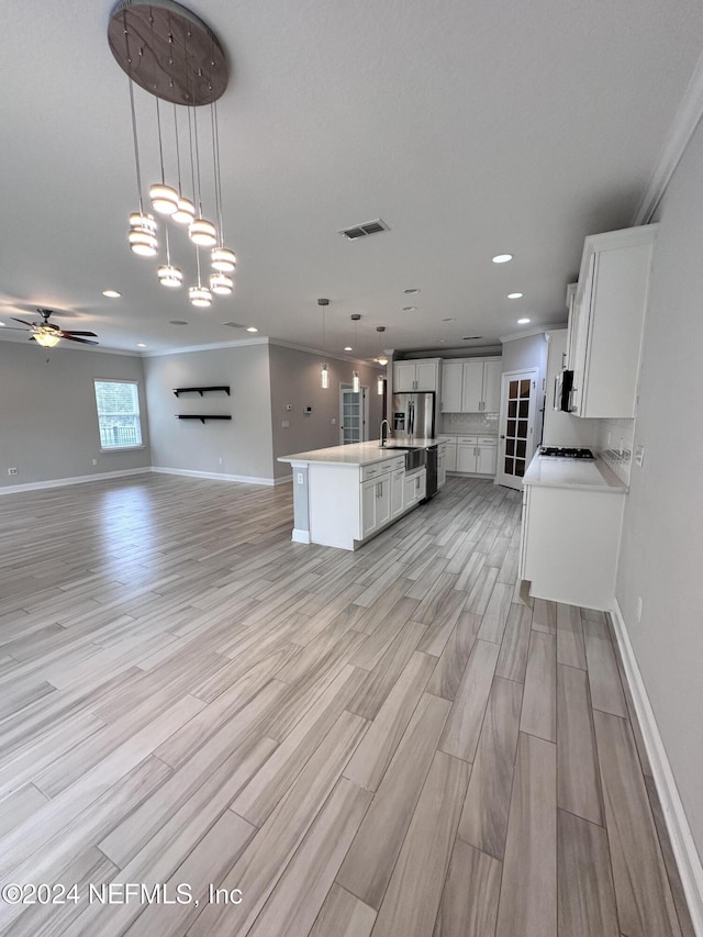 kitchen featuring pendant lighting, a center island with sink, white cabinetry, and light hardwood / wood-style floors