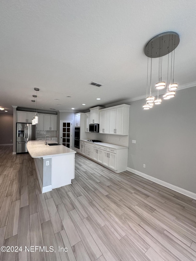 kitchen featuring light wood-type flooring, stainless steel appliances, crown molding, decorative light fixtures, and a large island