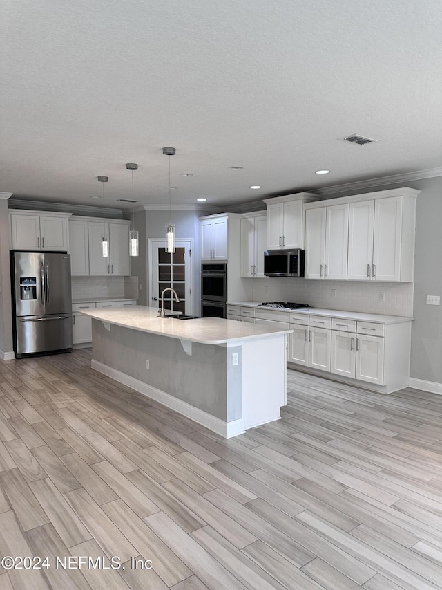 kitchen featuring white cabinets, appliances with stainless steel finishes, light hardwood / wood-style flooring, and pendant lighting