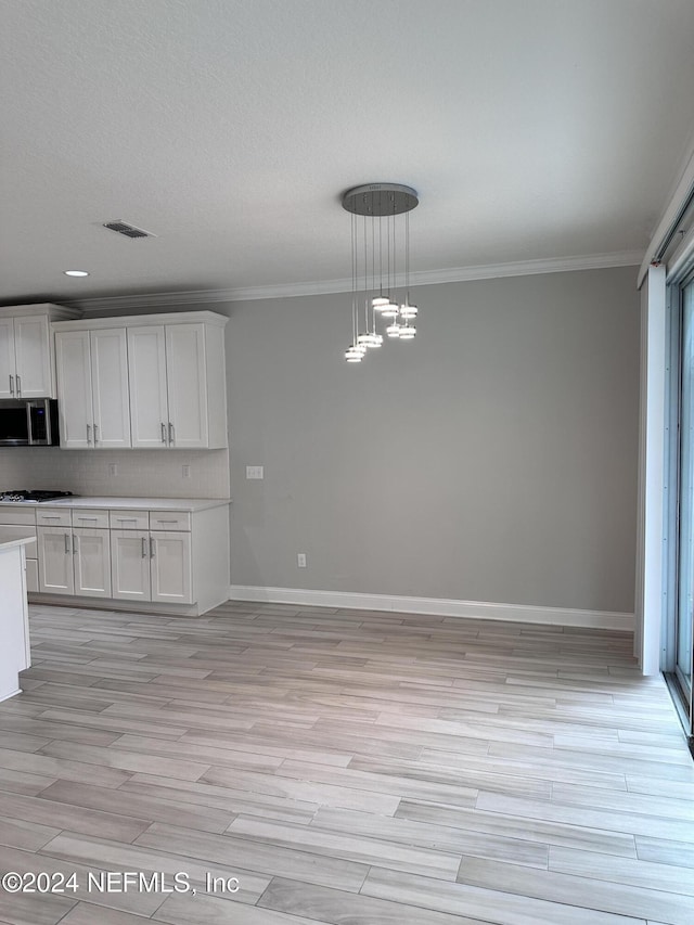 kitchen featuring pendant lighting, light hardwood / wood-style flooring, white cabinetry, and ornamental molding