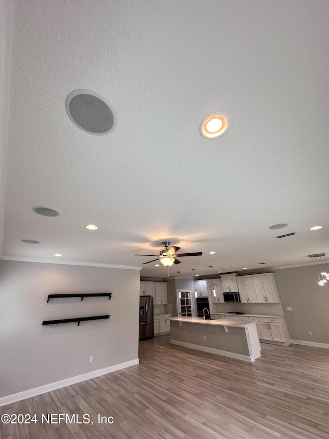 unfurnished living room with ceiling fan, a textured ceiling, and light hardwood / wood-style flooring