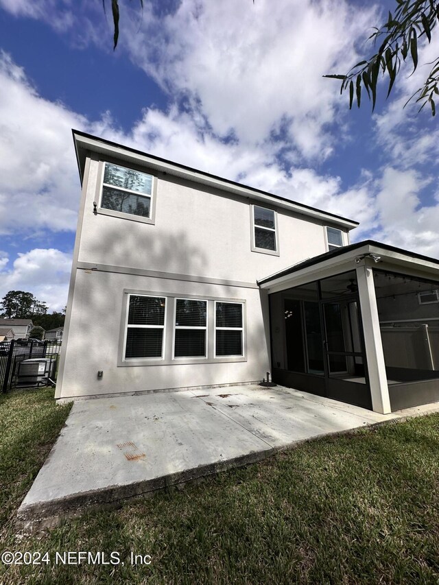 rear view of house featuring a lawn, a patio area, and a sunroom