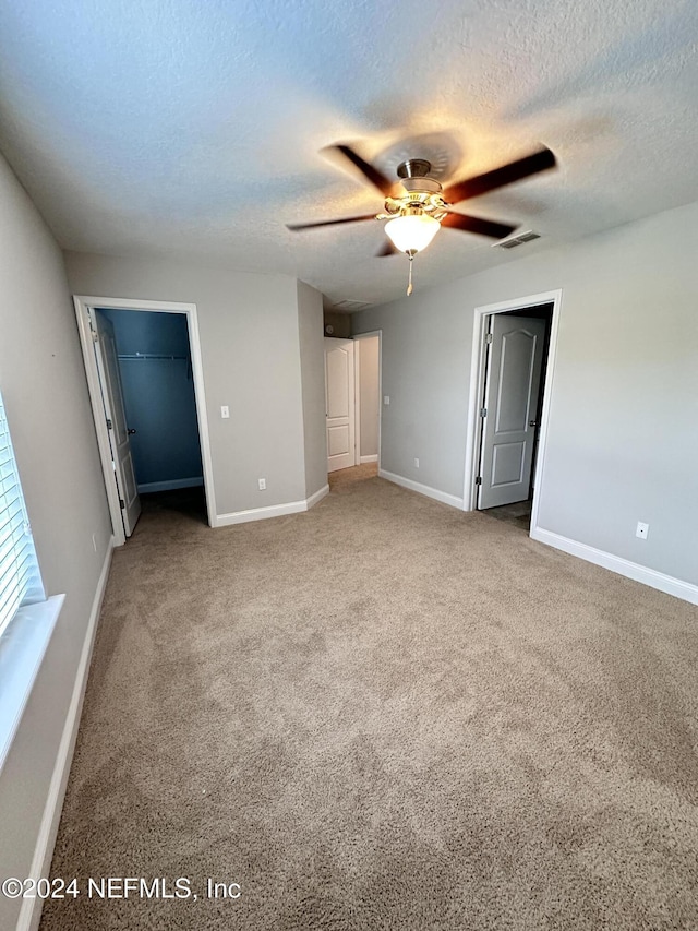 unfurnished bedroom featuring carpet flooring, a textured ceiling, and ceiling fan