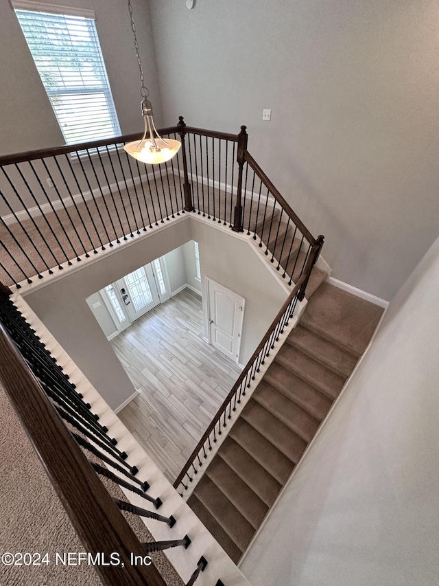 staircase with hardwood / wood-style floors and a towering ceiling