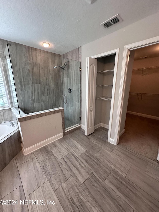 bathroom with a textured ceiling and independent shower and bath