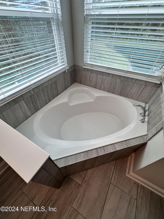 bathroom featuring tiled bath and a wealth of natural light