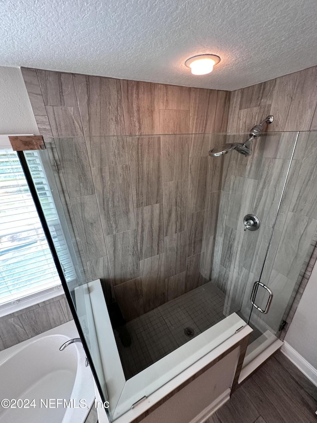 bathroom with separate shower and tub, hardwood / wood-style floors, and a textured ceiling