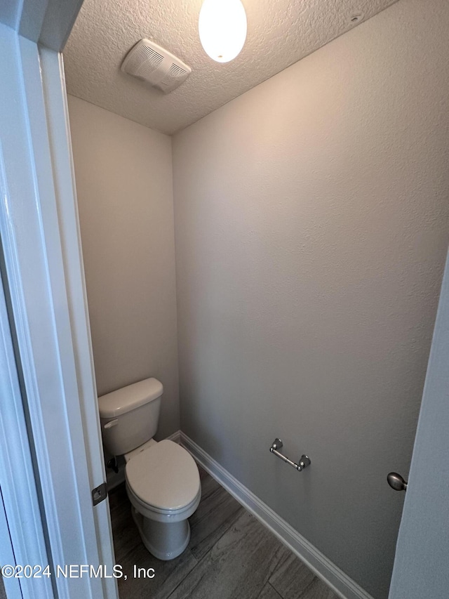 bathroom with hardwood / wood-style floors, a textured ceiling, and toilet