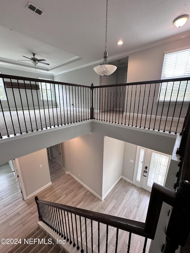 staircase with hardwood / wood-style floors, ceiling fan, crown molding, and a textured ceiling