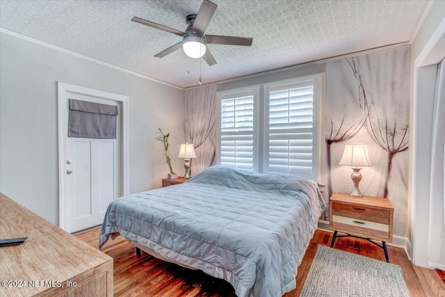 bedroom featuring wood-type flooring, a textured ceiling, ceiling fan, and ornamental molding