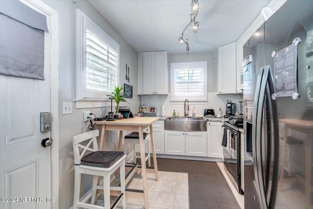 kitchen with black appliances, decorative backsplash, white cabinetry, and sink