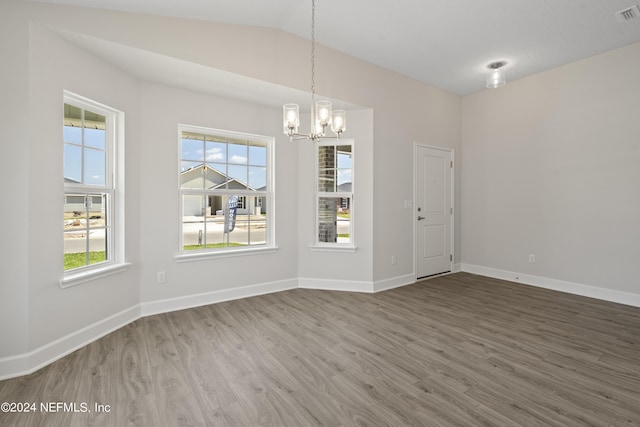 unfurnished dining area with wood-type flooring, lofted ceiling, and an inviting chandelier