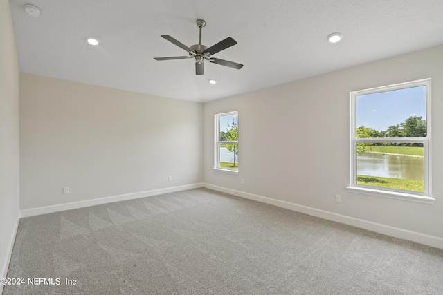 empty room featuring carpet flooring, a water view, and ceiling fan