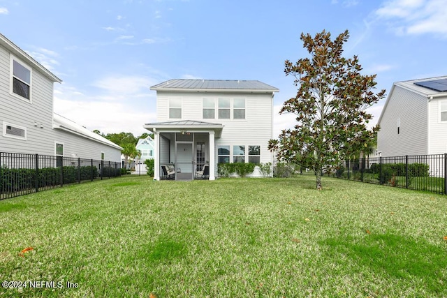 rear view of house featuring a yard and a sunroom