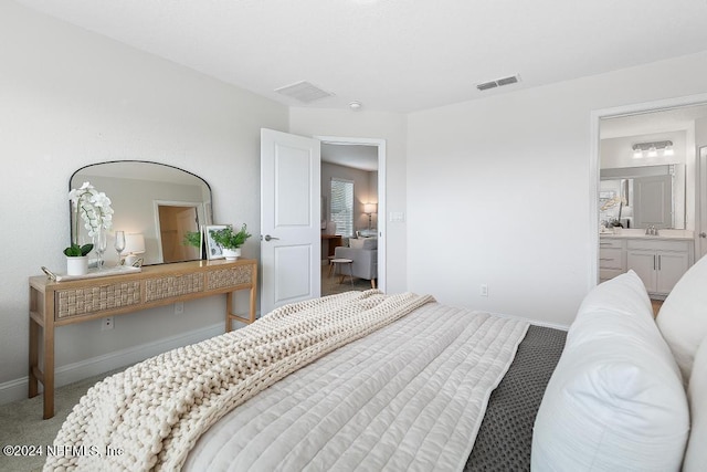 carpeted bedroom featuring ensuite bathroom and sink