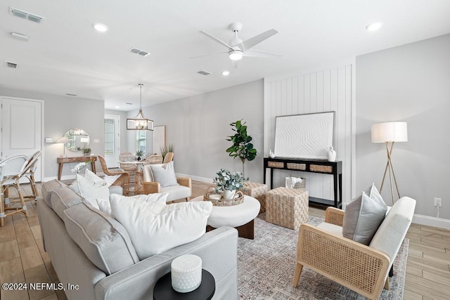 living room featuring light hardwood / wood-style floors and ceiling fan with notable chandelier