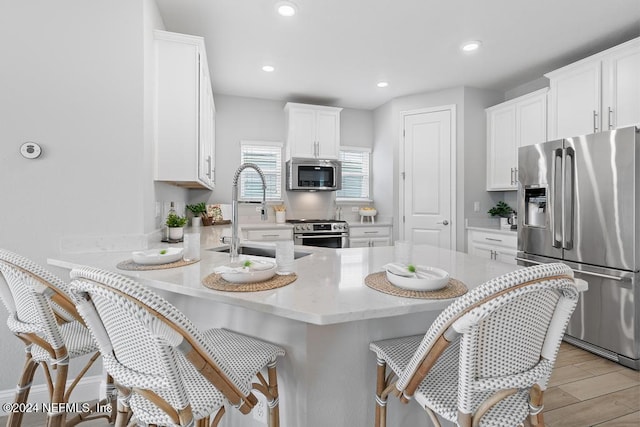 kitchen with white cabinets, stainless steel appliances, a breakfast bar area, and sink