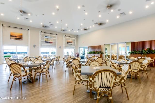 dining room featuring ceiling fan, light hardwood / wood-style floors, and a high ceiling