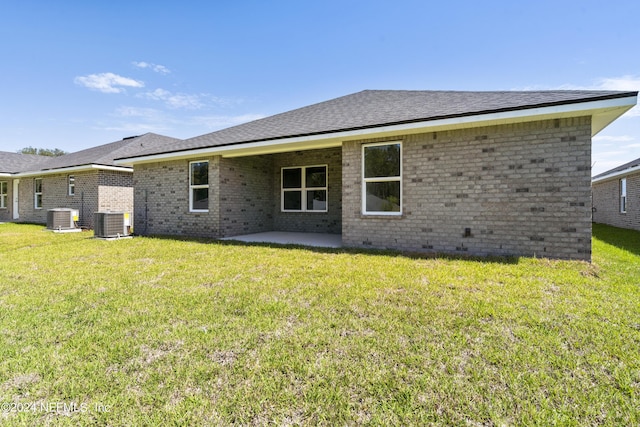 rear view of property featuring central AC unit, a patio, and a lawn