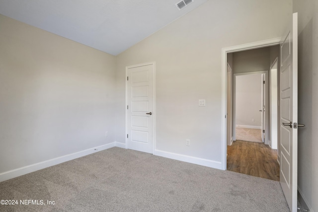 unfurnished bedroom with vaulted ceiling and carpet