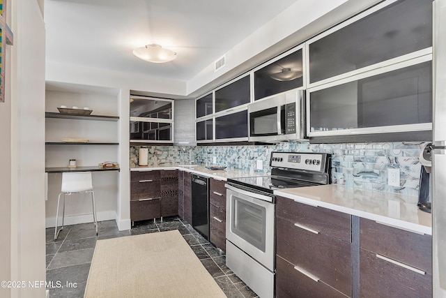 kitchen featuring dark brown cabinets, decorative backsplash, and stainless steel appliances