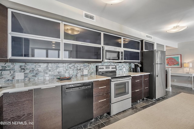 kitchen with backsplash, dark brown cabinets, dark tile patterned floors, and appliances with stainless steel finishes