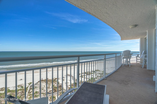 balcony with a water view and a view of the beach