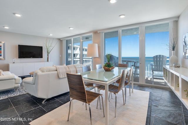 dining space featuring floor to ceiling windows and a water view