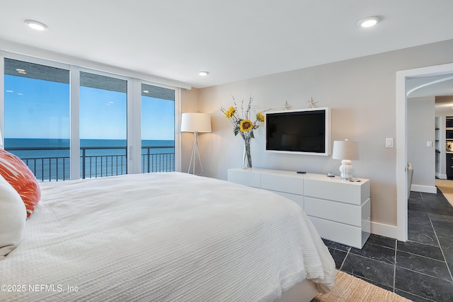 bedroom featuring access to outside, a water view, and floor to ceiling windows