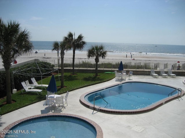 view of swimming pool featuring a view of the beach, a patio, and a water view