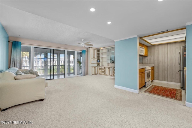 carpeted living room featuring ceiling fan, wood walls, and a textured ceiling