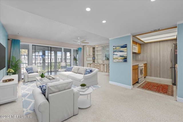 living room with a textured ceiling, ceiling fan, light colored carpet, and wood walls