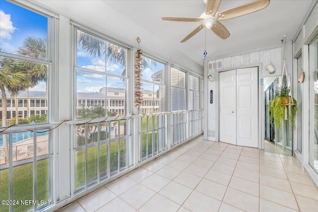 unfurnished sunroom featuring ceiling fan and plenty of natural light