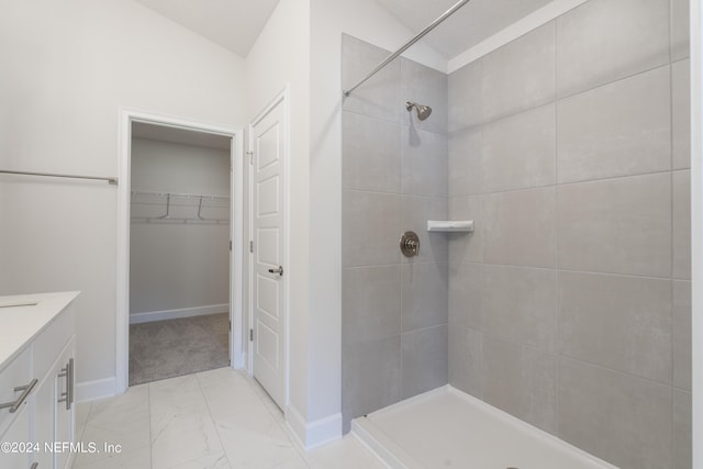 bathroom featuring vanity, lofted ceiling, and tiled shower