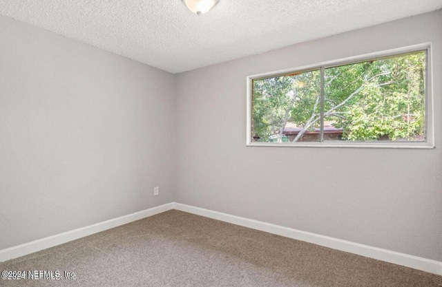 carpeted empty room featuring a textured ceiling