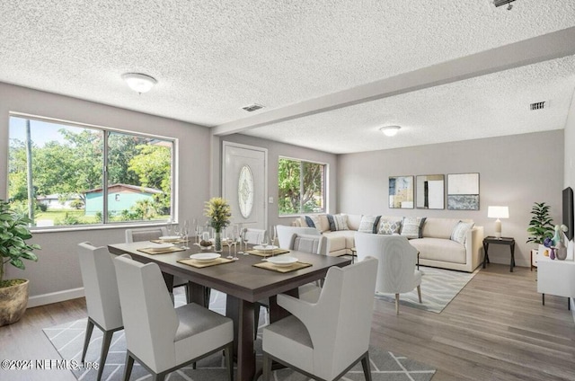 dining area with a healthy amount of sunlight, a textured ceiling, and wood-type flooring